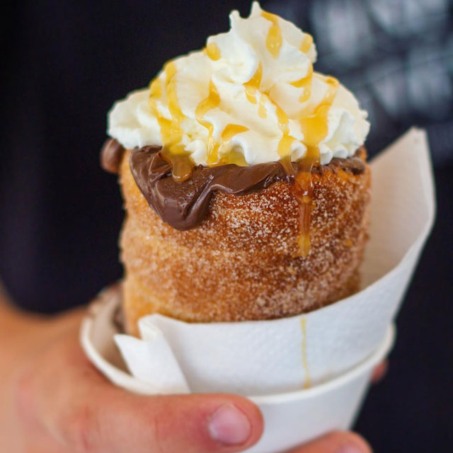 Baked cinnamon dough cone filled with Nutella, topped with whipped cream and caramel syrup